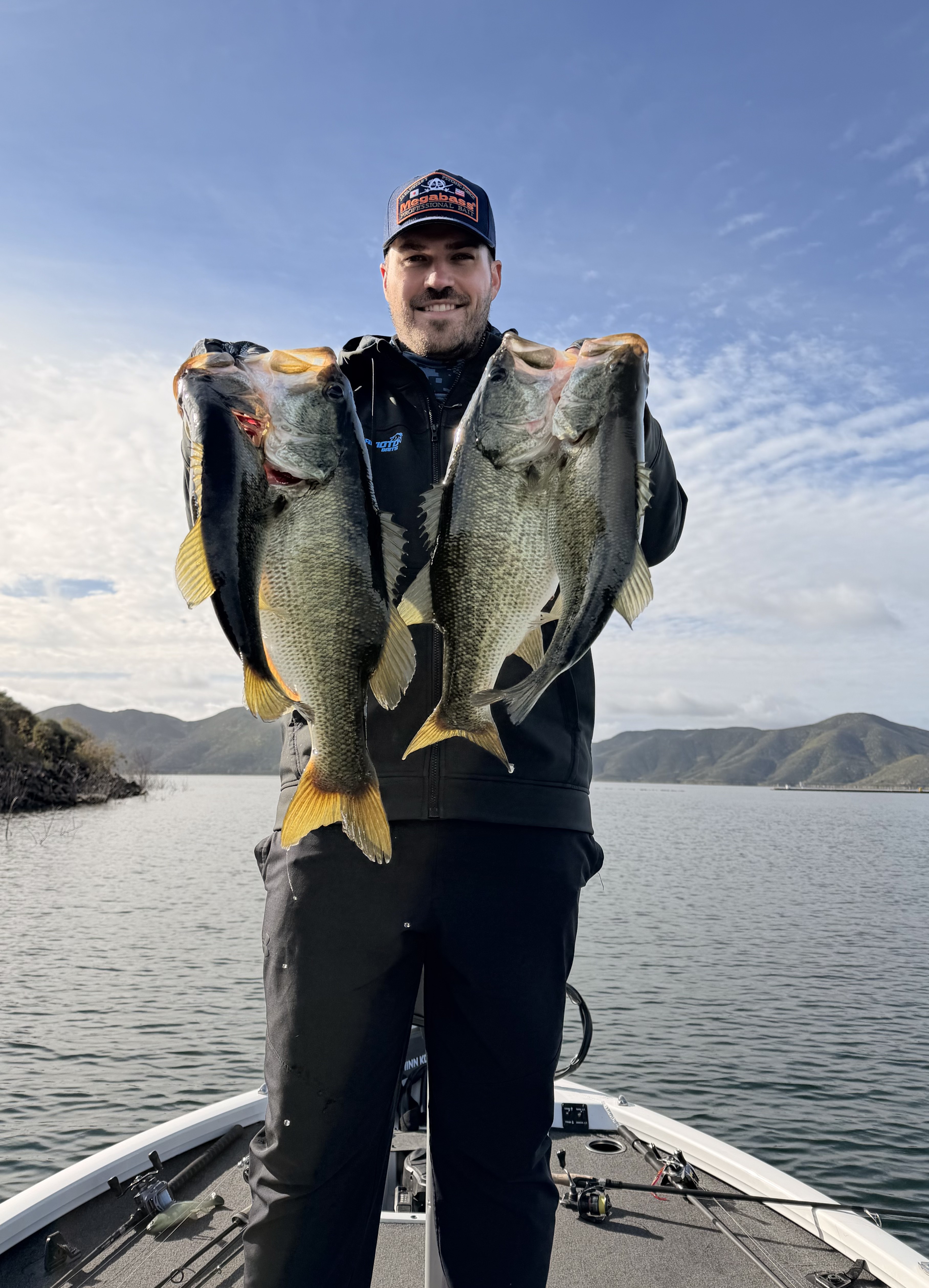 TJ LeClair holding several largemouth bass on a bass boat
