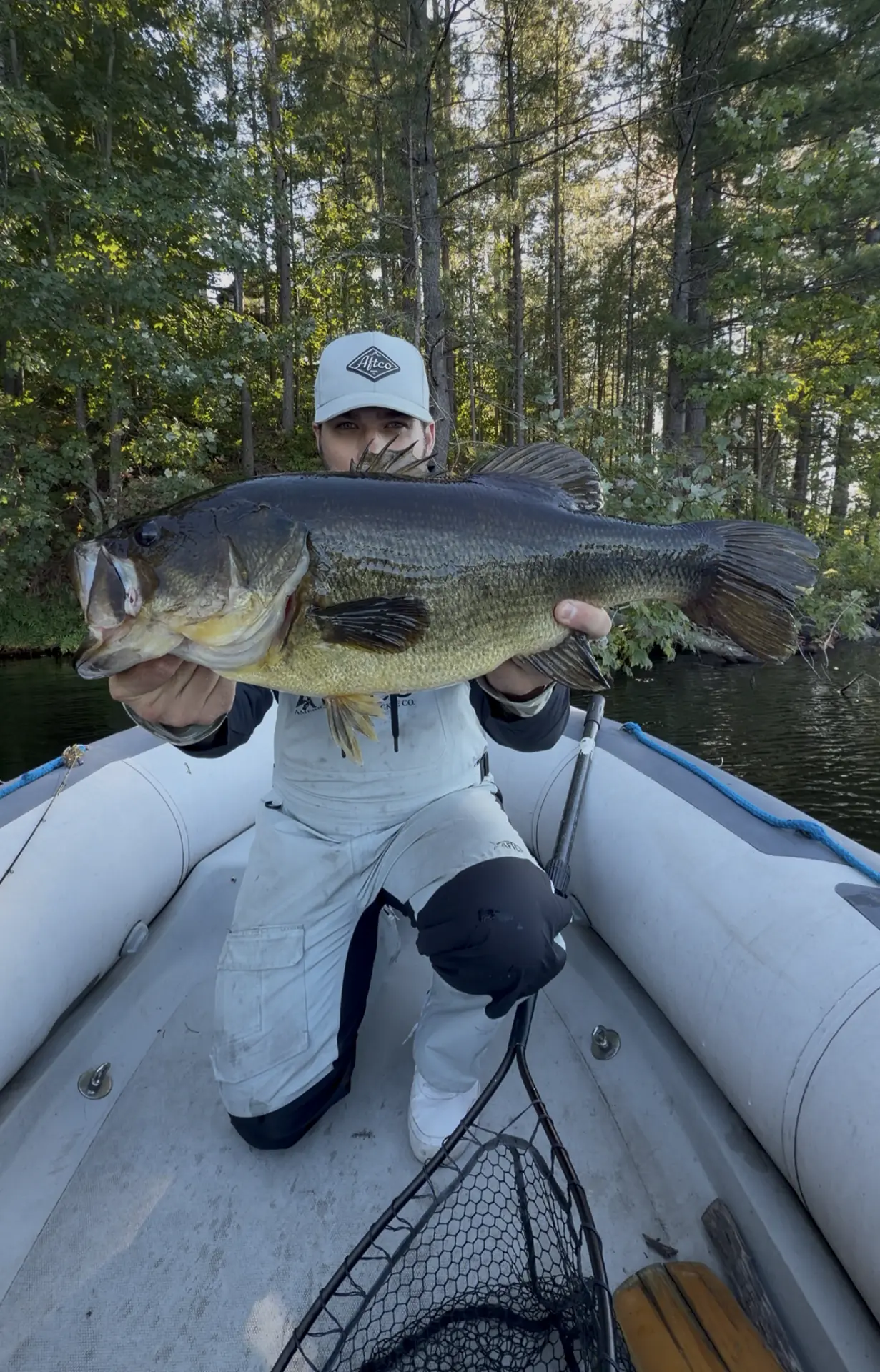 TJ LeClair kneeling in the boat with a large largemouth bass