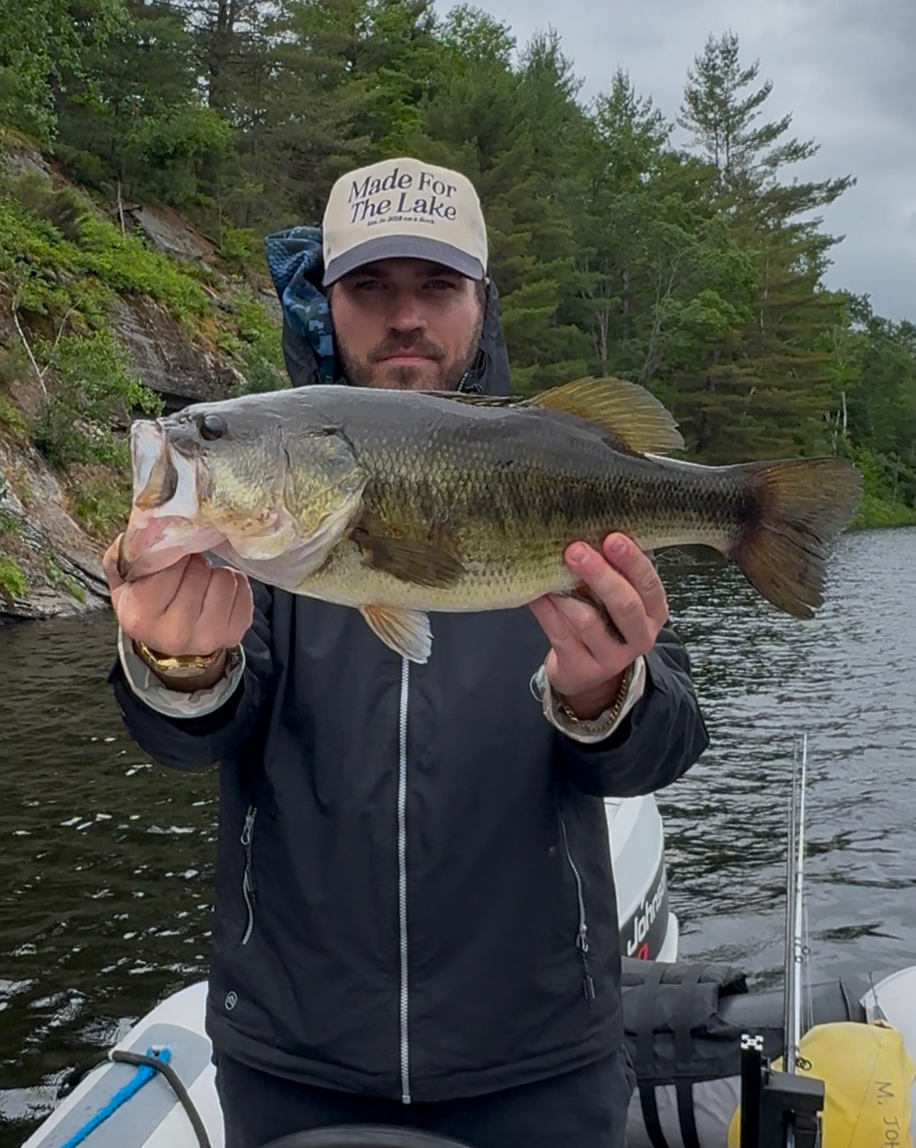 TJ LeClair holding a largemouth bass on a rain-grey Muskoka lake