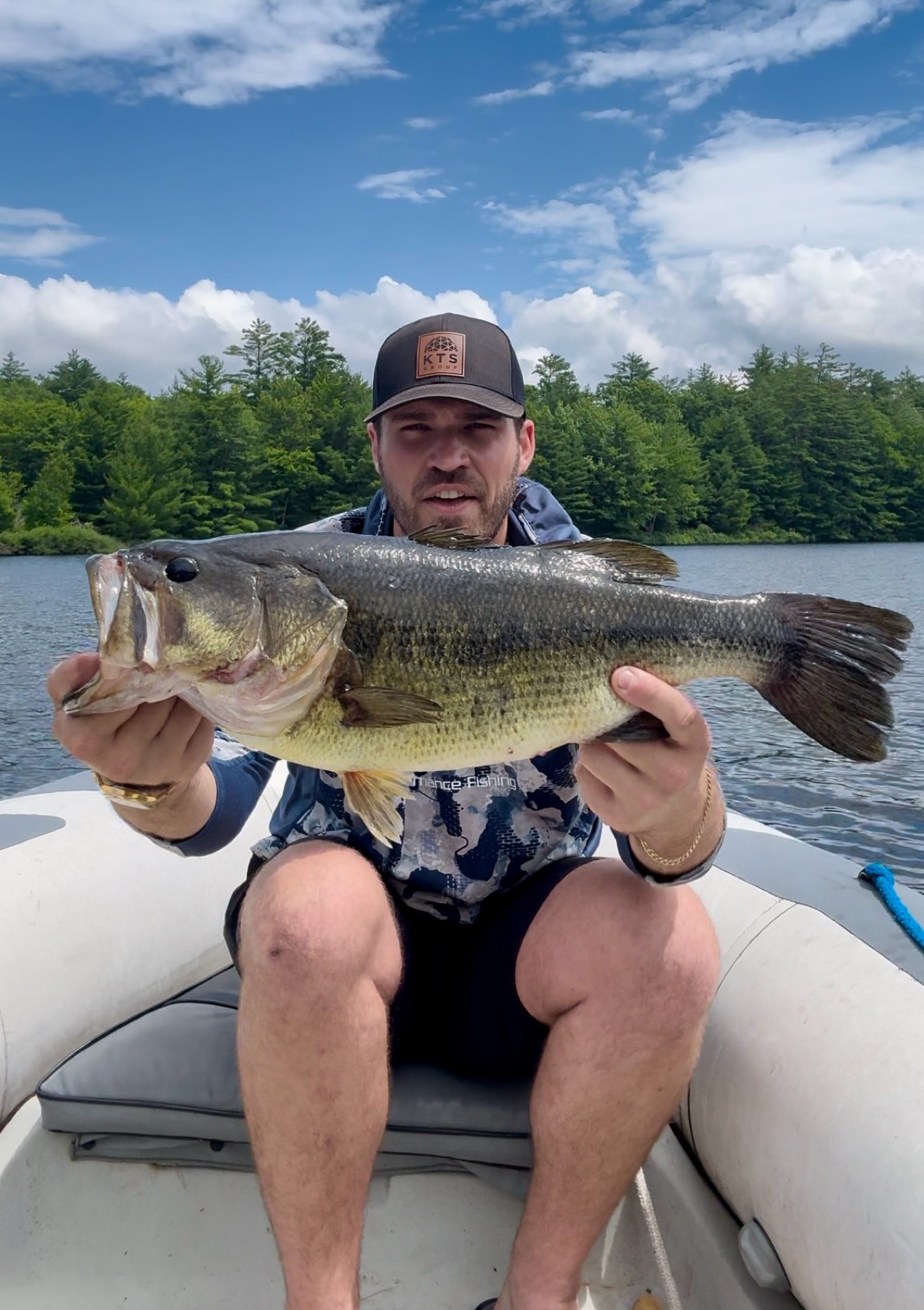TJ LeClair holding a largemouth bass under a summer sky