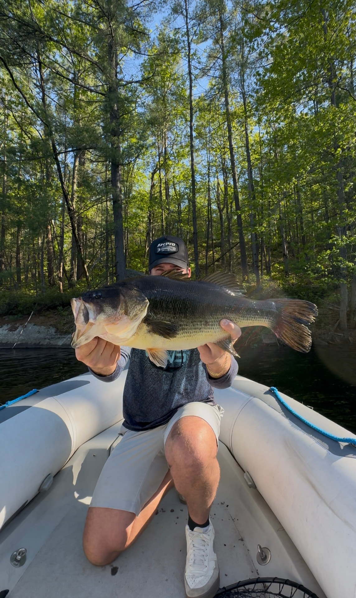 TJ LeClair kneeling on the boat with a largemouth bass