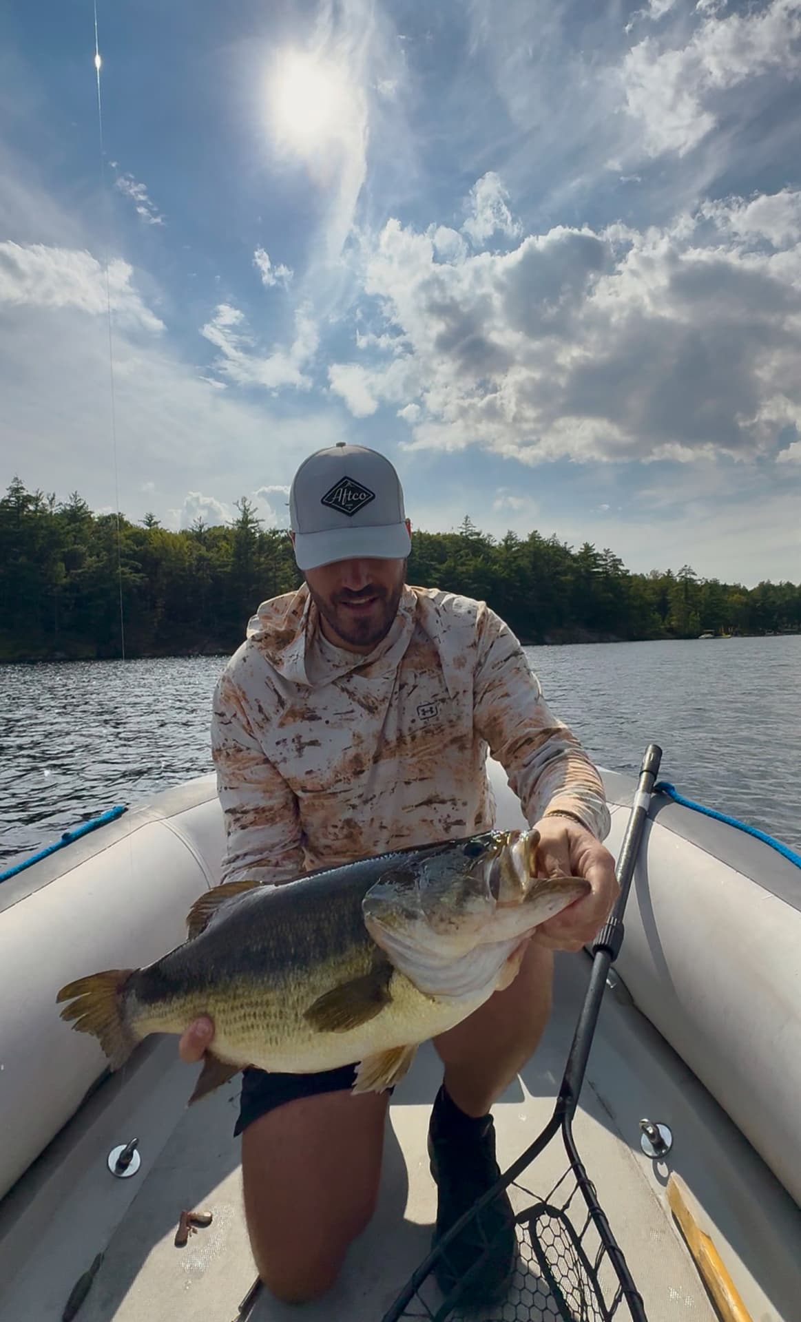 TJ LeClair kneeling in the boat with a large largemouth bass